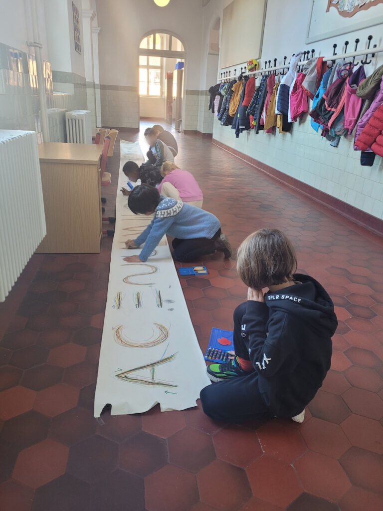 Kinder bemalen ein Papierbanner im Flur der Luitpoldschule Ansbach